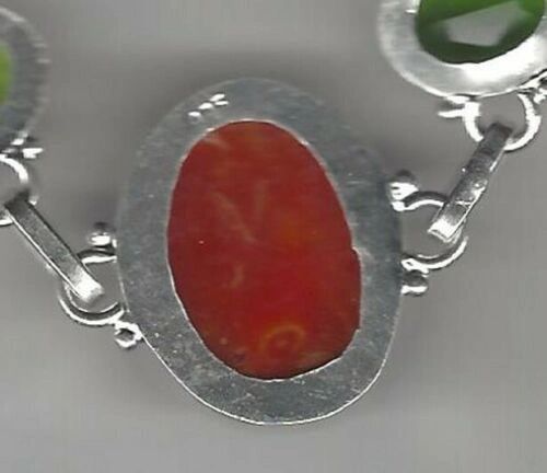 A silver bracelet with an orange stone on it.