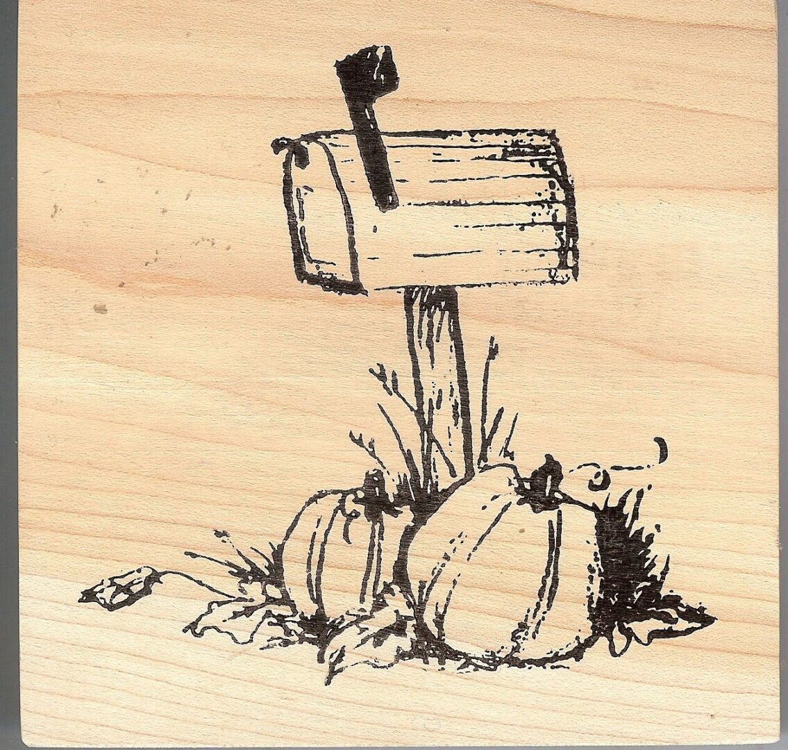 A wooden block with a drawing of a mailbox and pumpkins.