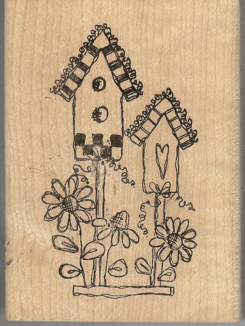 A wooden stamp with two houses and flowers.