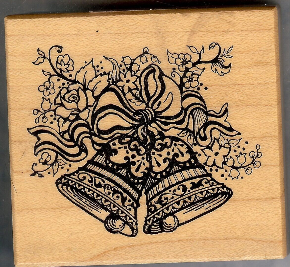 A wooden stamp with two bells and flowers.