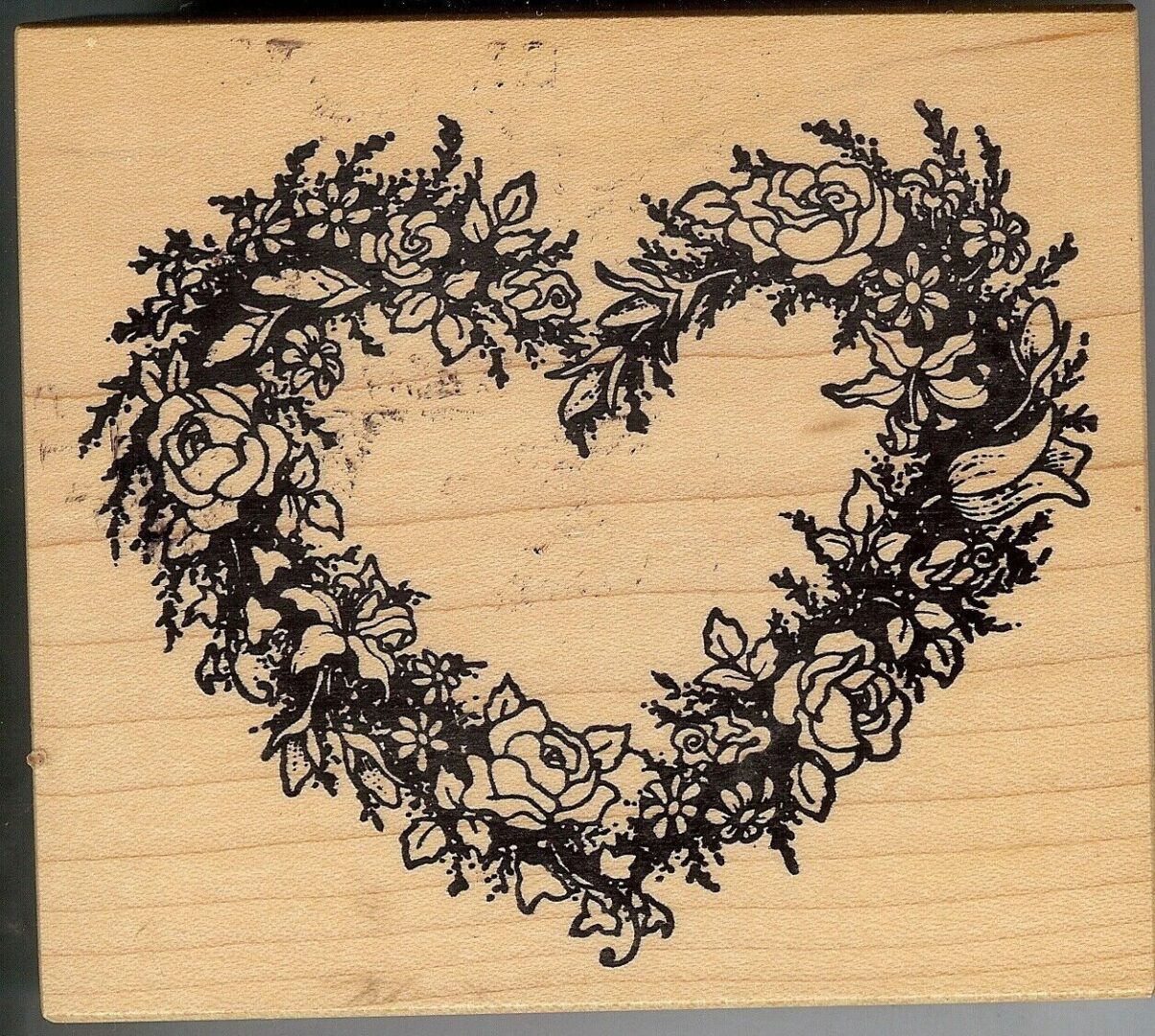 A heart shaped wreath of flowers on a piece of wood.